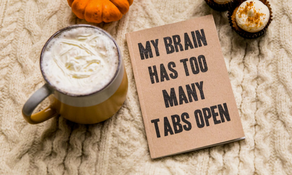 Photo of a coffee with a journal that's cover reads "My brain has too many tabs open"