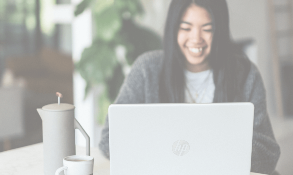 Woman smiling while on her laptop with coffee. Christian Stress Release Membership - Start Here Series. An on-demand video and audio library of mental health techniques to help Christian women release stress and find peace and balance in their everyday lives.