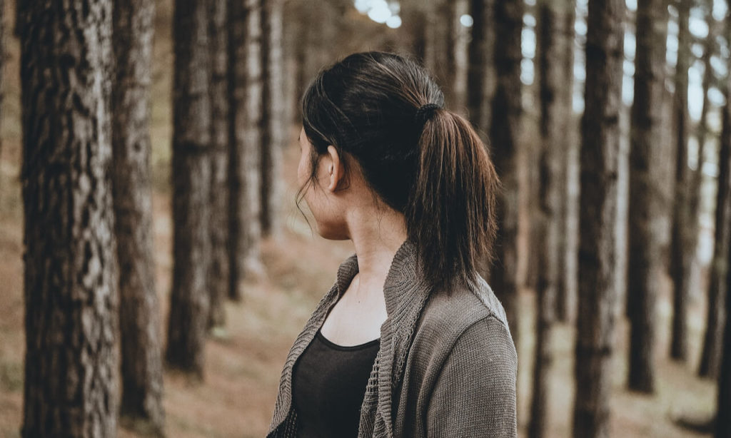 Woman standing in the woods looking back behind her
