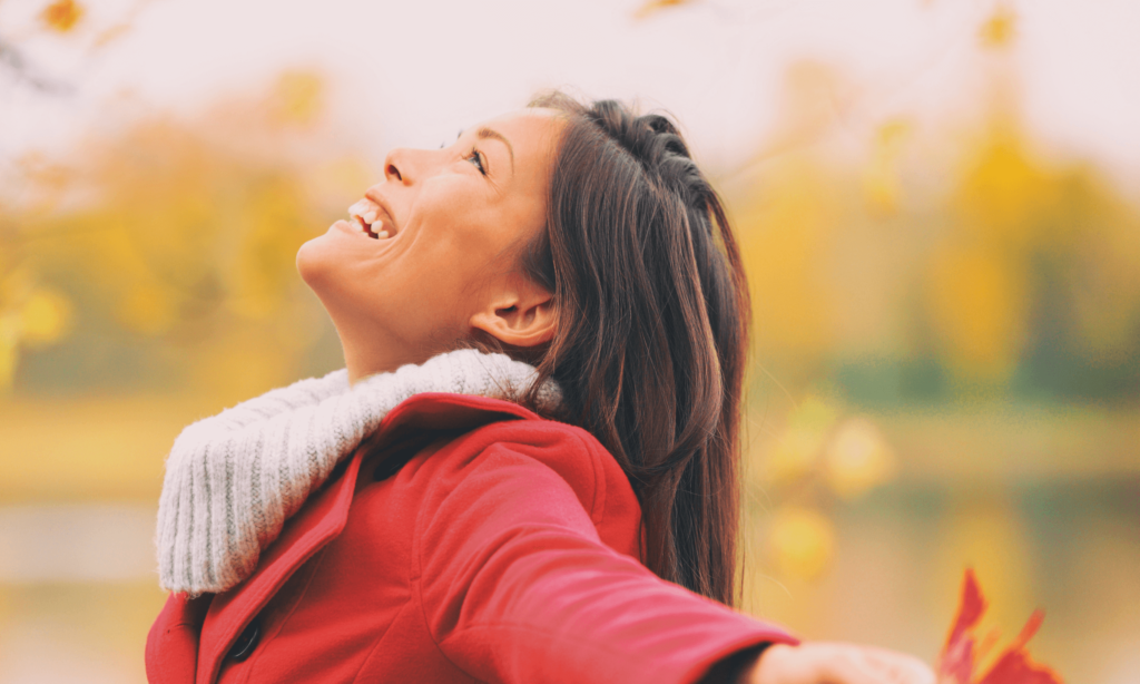 Woman looking up smiling with joy, arms stretched out wide