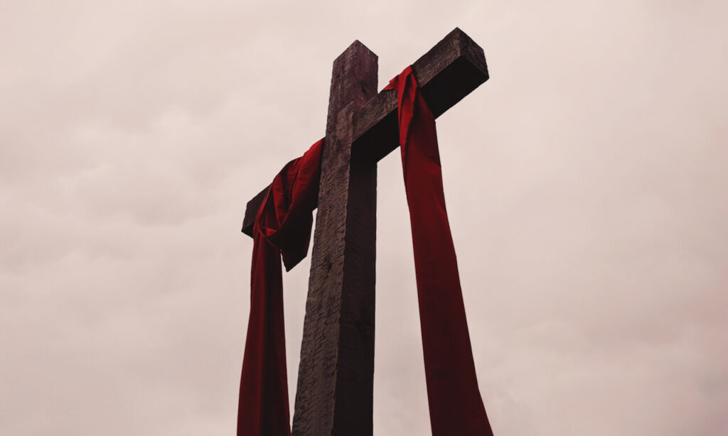 Wood cross with a red sash over the cross beams